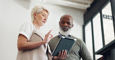 Business people, tablet and conversation working on report, reading communication or planning startup leadership strategy. Senior man, woman and discussion standing in lobby on digital tech device