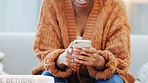 Woman sending a text message, browsing social media or surfing the internet on her phone while sitting in the living room at home. Closeup of the hands of a black female holding wireless technology