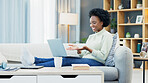 Happy black woman waving while using a laptop to make a video call in the living room. Young african american female excited to have a casual chat with friends or family at home during lockdown