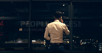 Business man, phone call and window at night in modern office building for global networking or negotiation. Finance, talk strategy rear and corporate worker using phone, communication and city bokeh