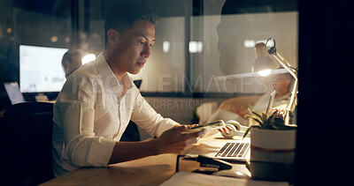 Asian businessman, laptop and phone at night working in marketing or advertising at office. Japanese employee man in web design at work on computer checking email, networking or online at workplace