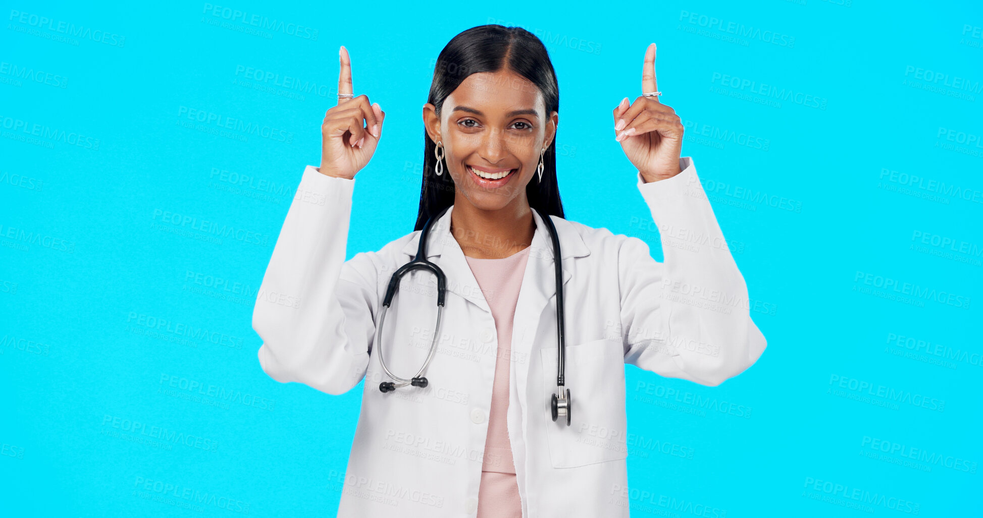 Buy stock photo Studio portrait, happy woman and doctor pointing up at medical info, hospital direction or pharmacy medicine commercial. Healthcare announcement, wellness brand logo and pharmacist on blue background
