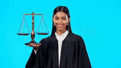 Buy stock photo Portrait, justice and scale with a woman judge in studio on a blue background for law or legal case. Smile, balance and a happy young indian advocate looking confident with her verdict on a trial
