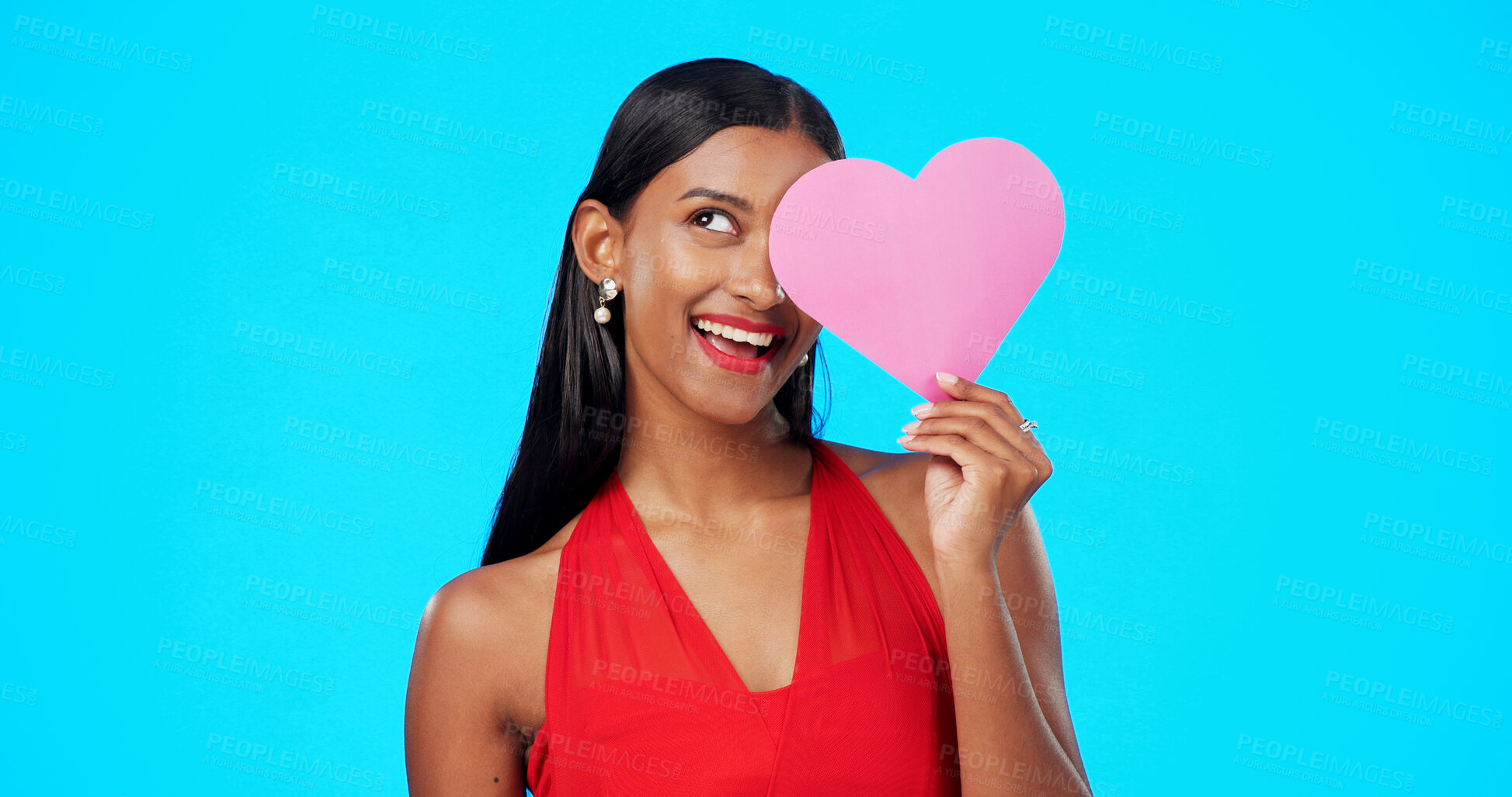 Buy stock photo Paper heart, happy and young woman in a studio for valentines day or anniversary emoji. Idea, romance and Indian female model with love sign for gift or present isolated by a blue background.