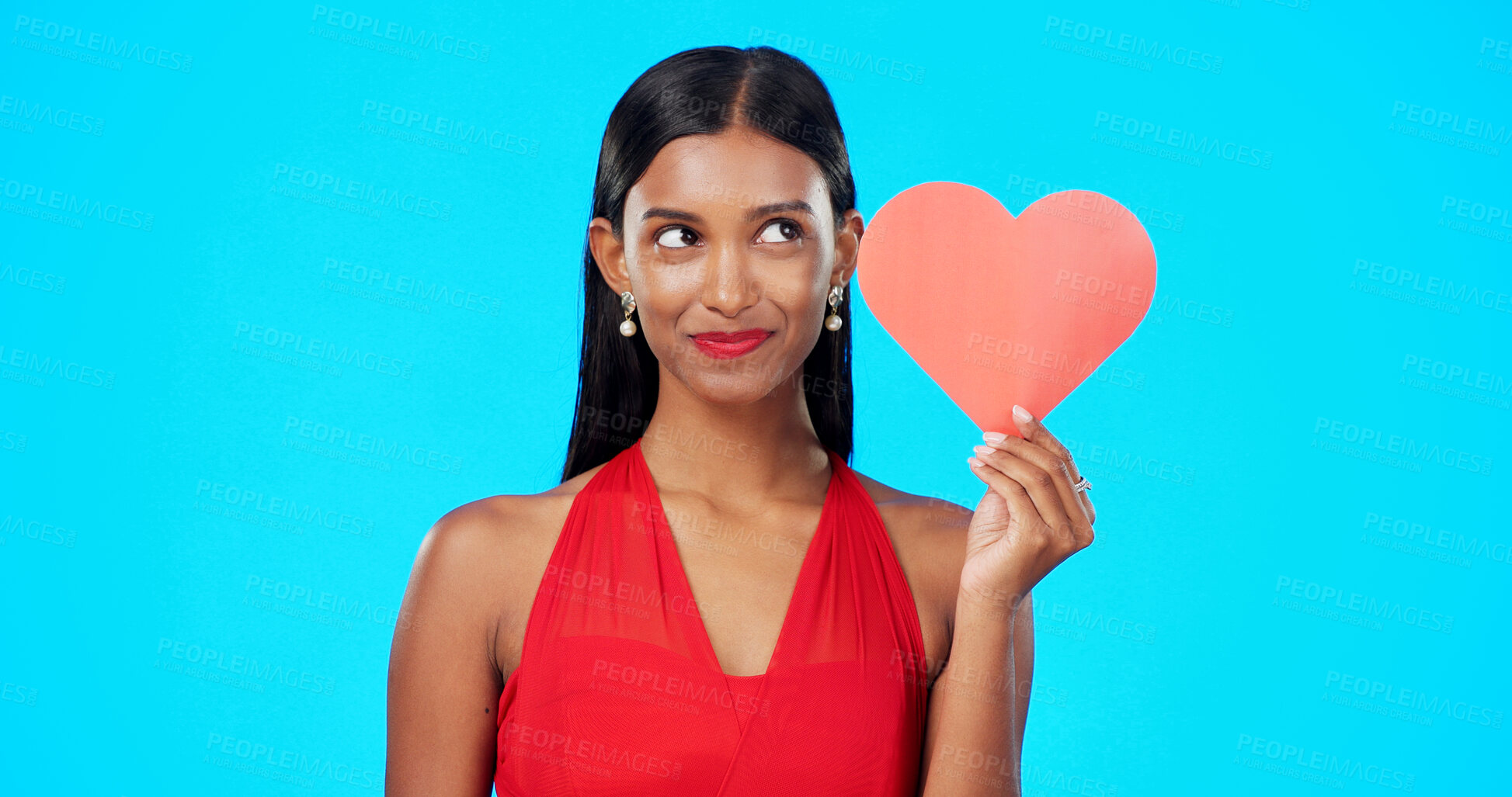Buy stock photo Paper heart, thinking and young woman in a studio for valentines day or anniversary emoji. Idea, romance and Indian female model with love sign for gift or present isolated by a blue background.