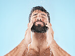 Man, shower and face cleaning for skincare hygiene, body care wellness and grooming health in blue background studio. Water splash, facial spa dermatology and cosmetics beauty or washing in morning