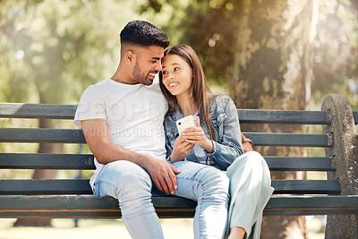 Buy stock photo Happy couple, phone and relaxing on park bench together browsing social media and bonding in nature. Man and woman smile in happiness for relationship on mobile smartphone in the summer outdoors