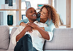 Couple, hug and laughing on sofa in home living room, bonding, relaxing and having fun. Interracial, love and funny black man and woman on couch embrace, happiness and enjoying quality time together