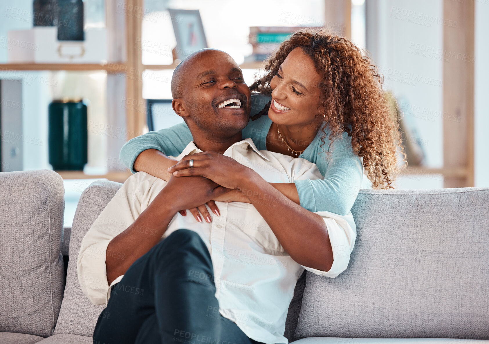 Buy stock photo Couple, hug and laughing on sofa in home living room, bonding, relaxing and having fun. Interracial, love and funny black man and woman on couch embrace, happiness and enjoying quality time together