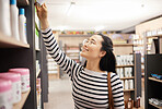 Shelf, shopping and Asian woman in store, smile and retail with decision, buying and products. Japanese female shopper,  buyer and happy lady in supermarket, choosing goods and items with happiness