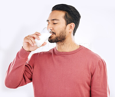 Buy stock photo Man drinking glass of milk in studio, white background and backdrop for healthy dairy, smoothies and diet. Male model, cup and calcium of smoothie, vanilla milkshake and nutrition of protein drink 