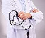 Doctor, hands and stethoscope of man with arms crossed in healthcare cardiology against gray studio background. Closeup of male medical professional holding tool for checkup or heart rate monitoring