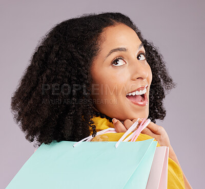 Buy stock photo Woman, face and smile with shopping bags for discount, sale or fashion against a gray studio background. Surprised female shopper smiling and holding gifts or shop accessories posing in happiness