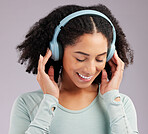 Woman, headphones and smile listening to music in joy against a gray studio background. Happy and fun female model smiling and relaxing in happiness with headset for audio track, sound or podcast