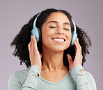 Happy woman, headphones and smile listening to music in joy against a gray studio background. Fun and calm female smiling and relaxing in happiness with headset for audio track, sound or podcast