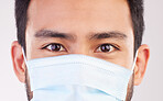 Doctor, portrait and man with mask for covid, compliance and safety in studio closeup. Facemask, prevention and eyes of male health expert at a clinic for help, treatment and healthcare control 