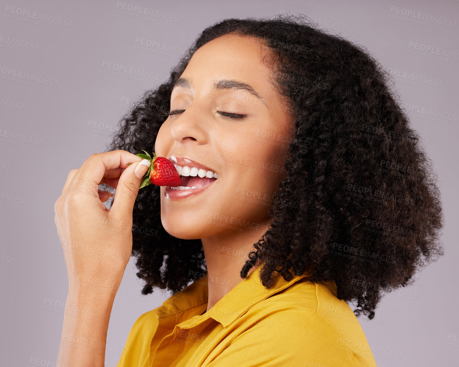 Buy stock photo Woman, face and eating strawberry for natural nutrition, dieting or healthy food against a gray studio background. Happy female smiling and enjoying tasty organic fruit for health, diet or wellness