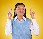 Hope, fingers crossed and woman model in studio wishing for success, winning or achievement. Happiness, smile and excited Indian female with a faith or luck hand gesture isolated by yellow background