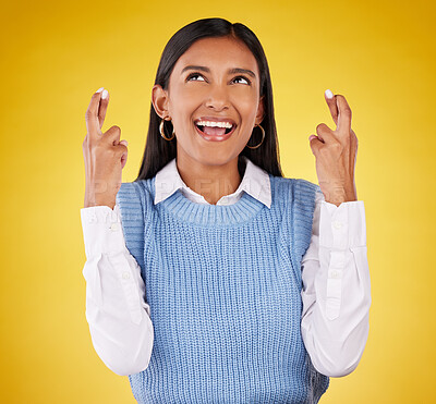Hope, fingers crossed and young woman in a studio wishing for success, winning or achievement. Happiness, smile and excited Indian female model with a faith hand gesture isolated by yellow background