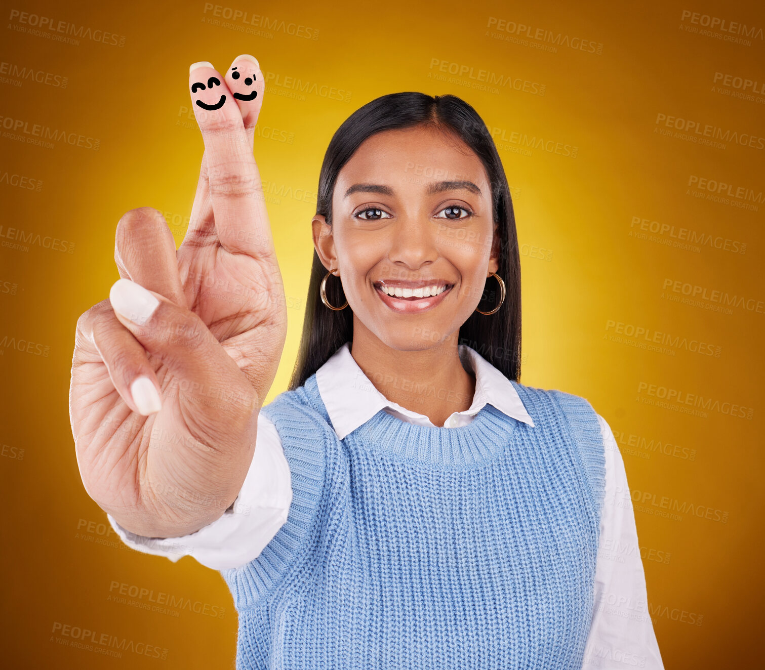 Buy stock photo Smiley face, fingers crossed and portrait of Indian woman in studio with drawing for hand sign, symbol and luck. Emoji mockup, yellow background and happy girl smile for wish, hope and lucky gesture