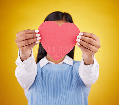 Buy stock photo Cover, paper and heart with woman in studio for love, support and romance. Valentines day, kindness and date with female hiding with symbol on yellow background for health, happiness and hope mockup