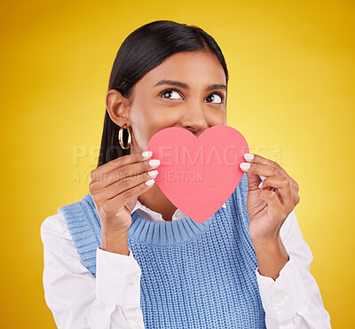 Buy stock photo Shy, paper and heart with woman in studio for love, support and romance. Valentines day, kindness and date with female and hiding with symbol on yellow background for health, happiness or hope mockup