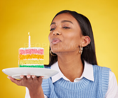 Buy stock photo Birthday, cake and woman blowing candle in studio for happy party celebration on yellow background. Happiness, gen z girl and candles in rainbow dessert to celebrate milestone, event or achievement.