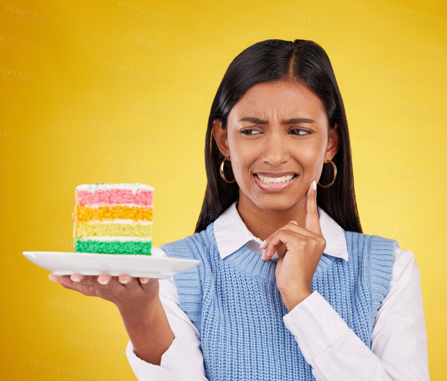 Buy stock photo Upset woman, rainbow cake and studio while thinking of birthday celebration, disaster or mistake. Face of Indian gen z female with dessert food with color, foul smell or bad idea on yellow background