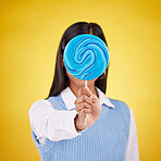 cover, lollipop and candy with woman in studio for sweets, colorful snack and food. Treats, dessert and sugar confectionery with female isolated on yellow background for diet, eating and hiding 