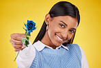 Portrait, love and rose with a woman on a yellow background in studio for valentines day. Face, blue flower and smile with a happy young female holding a plant for romance or anniversary celebration