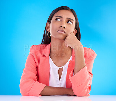 Buy stock photo Thinking, confused and a business woman on a blue background in studio for problem solving at her desk. Idea, doubt and decision with a young female employee contemplating a thought, choice or option