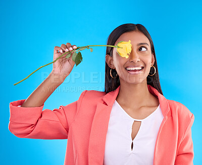 Buy stock photo Rose, love and valentines day with a woman on a blue background in studio thinking about romance. Spring, gift and yellow flower with an attractive young female holding a plant for summer or growth