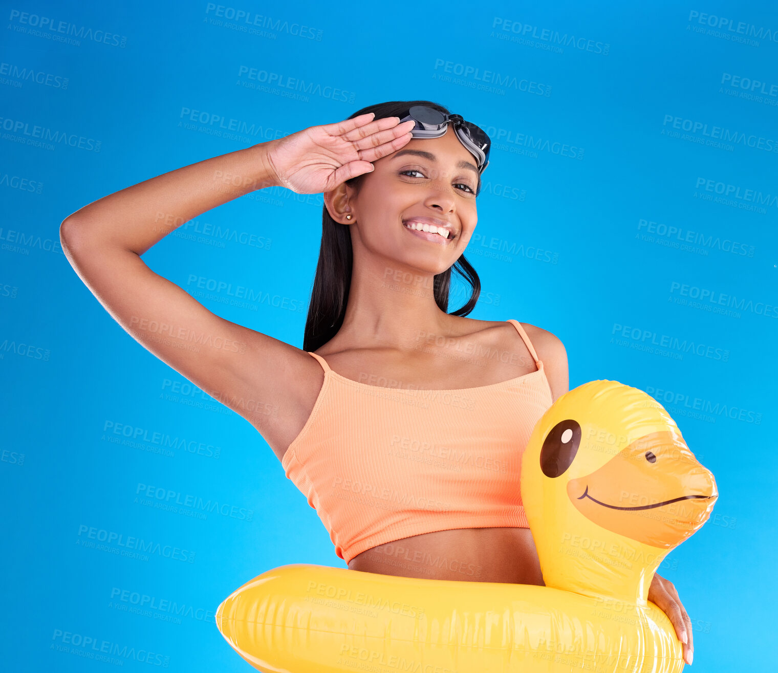 Buy stock photo Happy woman, portrait smile and swimming vacation in salute standing with inflatable duck against a blue studio background. Excited female smiling in swimwear ready for swim, pool or travel on mockup