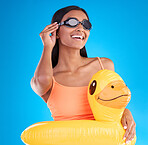 Goggles, smile and rubber duck with a woman on a blue background in studio ready for summer swimming. Happy, travel and vacation with an attractive young female looking excited to relax or swim