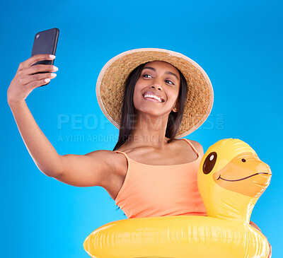 Buy stock photo Happy woman, portrait smile and selfie on swimming vacation for profile picture with inflatable duck against a blue studio background. Excited female smiling in swimwear for photo, travel or trip