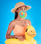 Portrait, lollipop and rubber duck with a woman on a blue background in studio ready for summer swimming. Happy, travel and vacation with an attractive young female looking excited to relax or swim