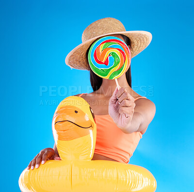 Buy stock photo Pool float, woman and lollipop in a studio with sweet snack and swimsuit with food. Isolated, blue background and holiday outfit of a young female hiding with sweets, candy or rubber duck feeling fun