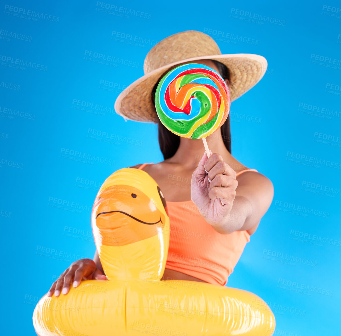 Buy stock photo Pool float, woman and lollipop in a studio with sweet snack and swimsuit with food. Isolated, blue background and holiday outfit of a young female hiding with sweets, candy or rubber duck feeling fun