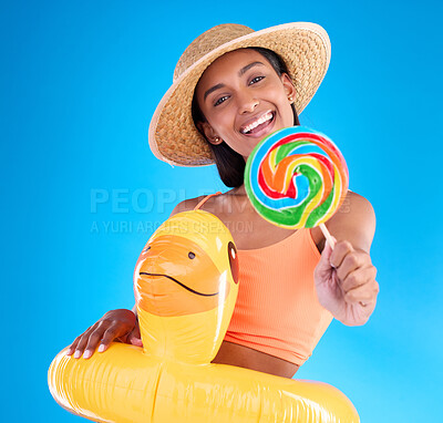 Buy stock photo Portrait, lollipop and inflatable duck with a woman on a blue background in studio ready for summer swimming. Happy, travel and vacation with an attractive young female looking excited to relax