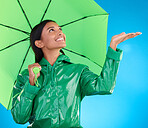 Happy, winter and a woman with an umbrella for the rain isolated on a blue background. Smile, insurance and a girl feeling for drops of water, bad weather and drizzling with shelter on a backdrop