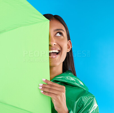 Buy stock photo Umbrella, fun or happy woman in playful studio with raincoat, silly or happiness mockup. Goofy, face or excited female on isolated blue background or looking with smile, curious or thinking expresion