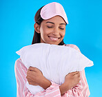 Bedtime, happy and a woman hugging a pillow isolated on a blue background in a studio. Smile, comfy and a girl ready for sleep, nap or slumber in pyjamas for comfort and coziness on a backdrop