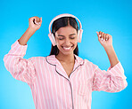 Happy, dance and woman in pajamas, headphones and cheerful on a blue studio background. Female, joyful and lady with headset, waking up and dancing with sounds, streaming music and songs for movement