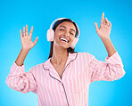 Smile, dance and woman in pajamas, headphones and inspiration against a blue studio background. Female, happy and lady with headset, waking up and dancing for motivation, wellness and streaming music