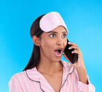 Phone call, shock and woman in pajamas in a studio with shocking, winning or good news. Surprise, happy and Indian female model on a mobile conversation with a wtf, omg or wow face by blue background
