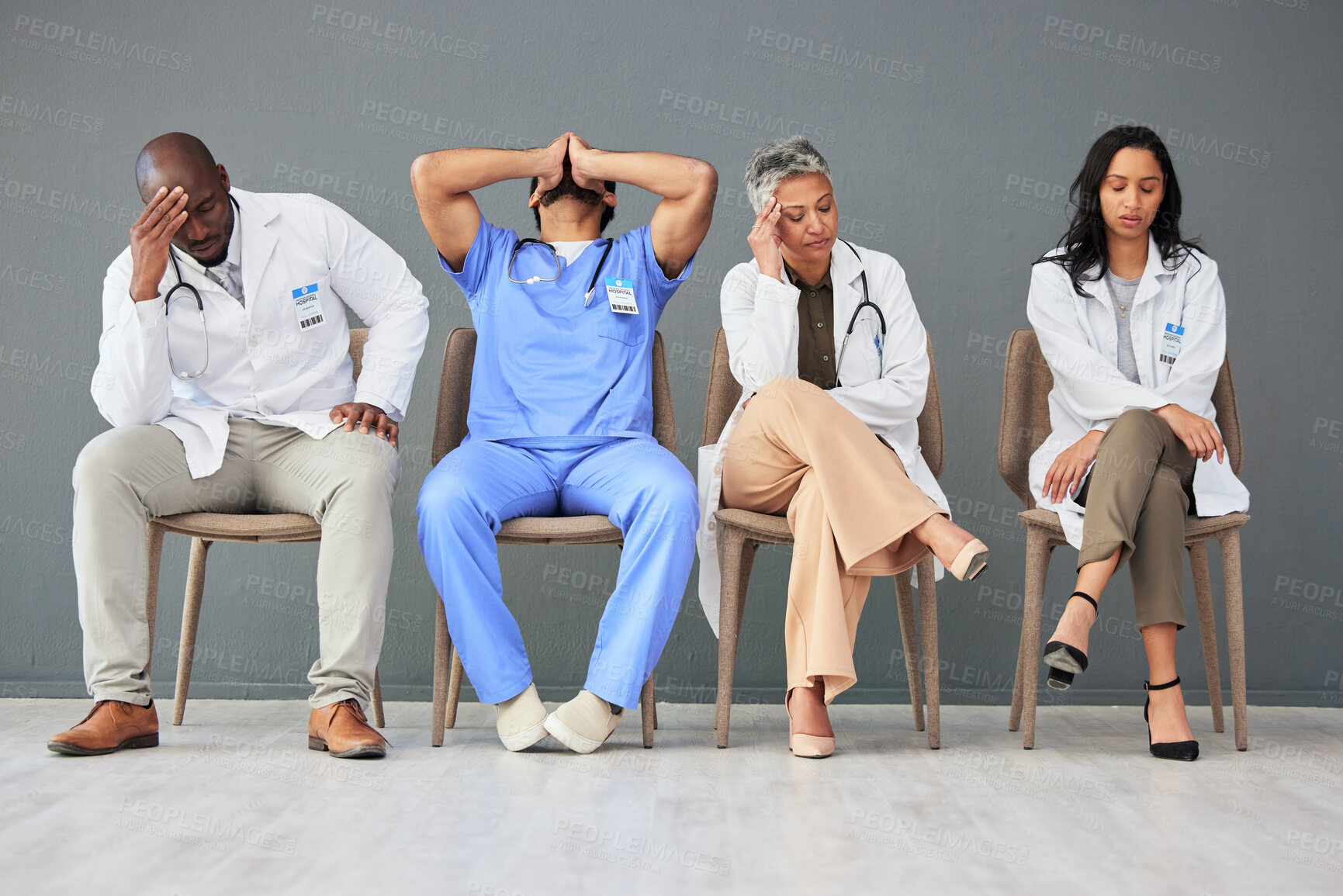 Buy stock photo Exhausted, tired and doctors waiting in the hospital with frustration, sad and burnout. Upset, professional and team of healthcare workers sitting in a line in a hallway for meeting in medical clinic