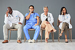 Tired, team and doctors waiting in the hospital with frustration, sad and burnout. Yawn, stress and group of professional healthcare workers sitting in a line in hallway for meeting in medical clinic