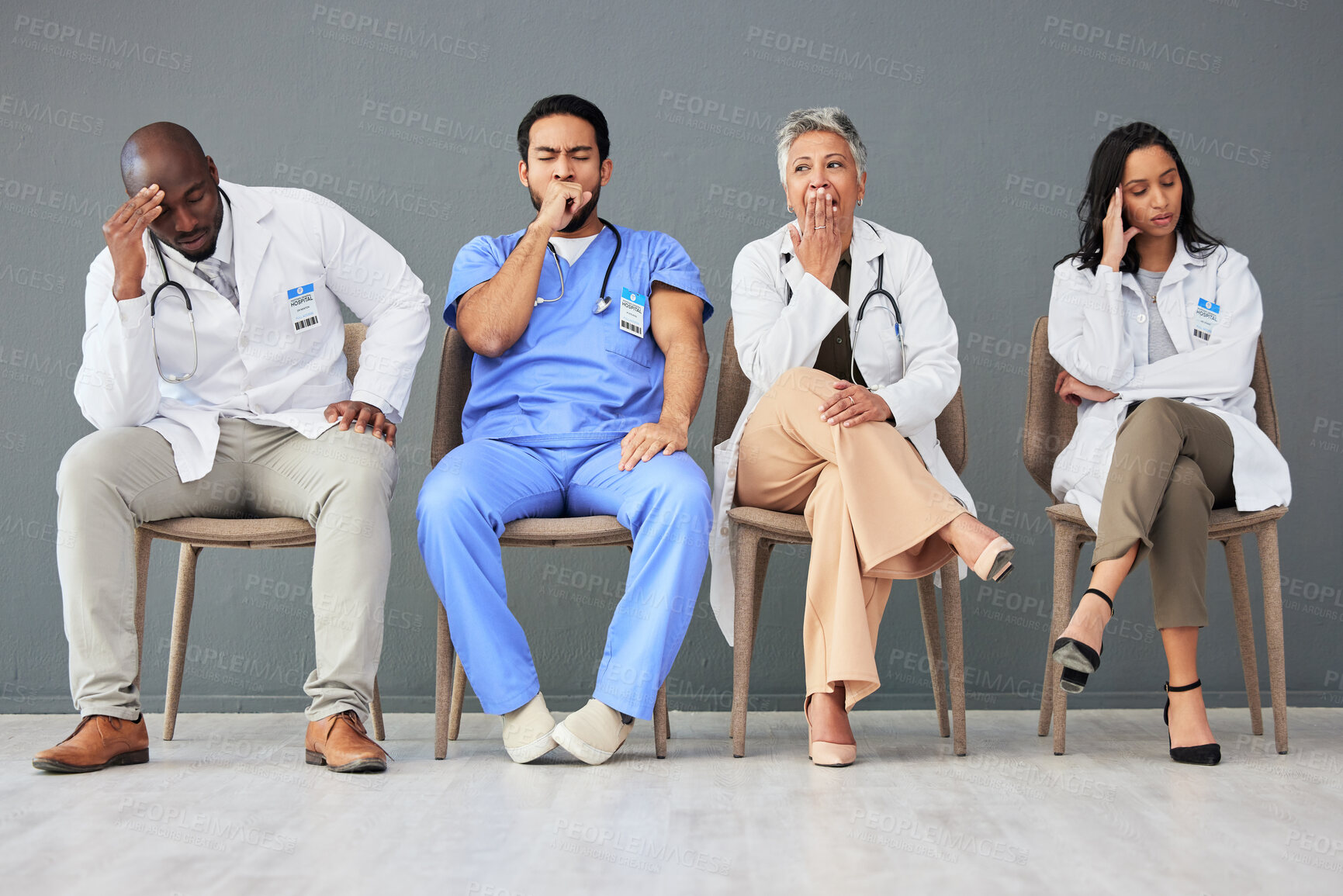 Buy stock photo Tired, team and doctors waiting in the hospital with frustration, sad and burnout. Yawn, people and group of stressed professional healthcare workers sitting in a line in hallway in a medical clinic.