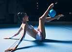 Woman, gymnastics and legs with ball for dancer performance, competition training or dark sports arena. Female athlete, rhythmic movement and creative talent in solo concert, agility skill or balance