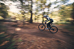Bicycle, mountain bike and man cycling in the forest or woods fast, speed and adrenaline with motion blur. Extreme sports, actions and rider cycling for exercise, fitness and workout in nature